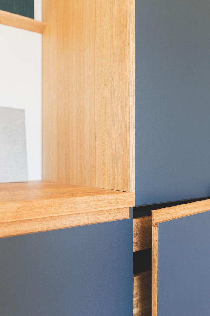 Nahaufnahme eines modernen Holzregals mit hellem Holz und dunkelblauen Schränken, das klare Linien und minimalistisches Design hervorhebt.