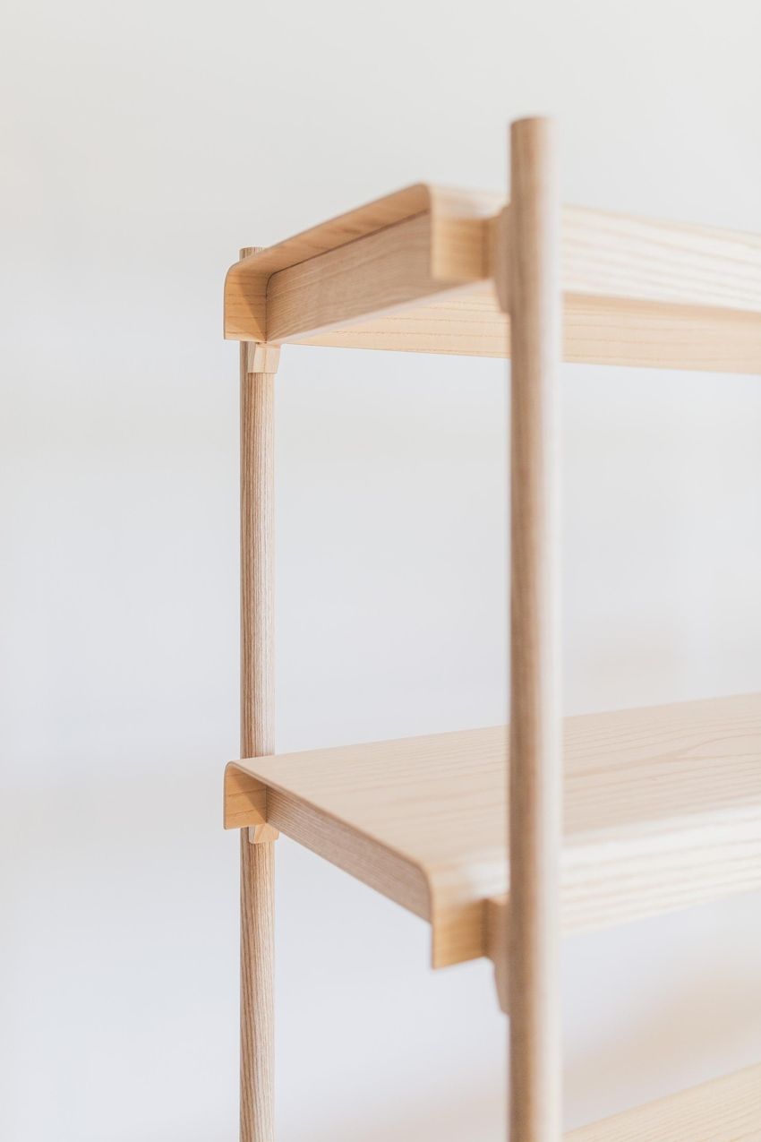 Nahaufnahme eines minimalistischen Holzregals mit glatten, abgerundeten Kanten und hellem Holz vor einem weichen, neutralen Hintergrund.