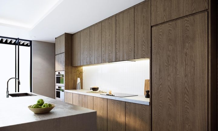 Die moderne Küche verfügt über elegante Holzschränke, eine geräumige Kochinsel mit einer Schale grüner Äpfel und eine helle Unterschrankbeleuchtung.